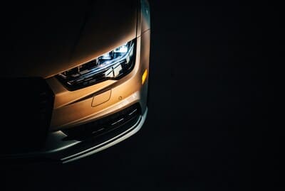 L'avant d'une voiture illuminé dans l'obscurité, mettant en valeur ses phares brillants. 