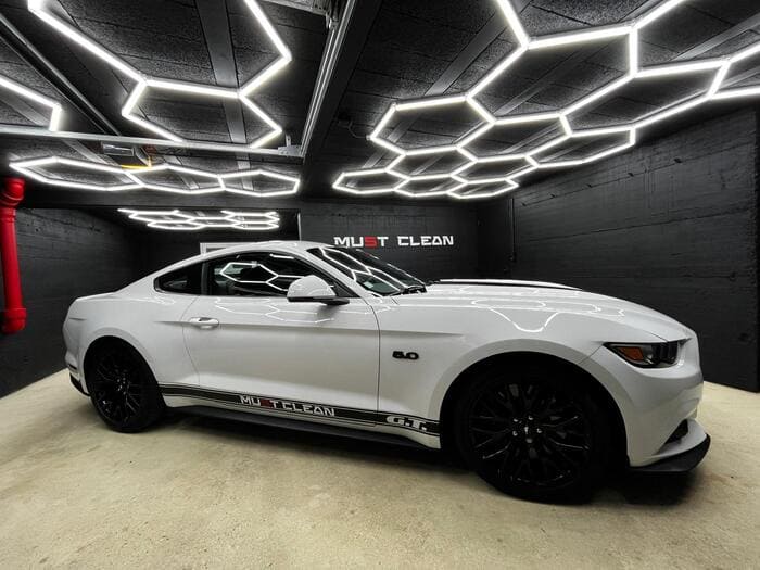 Une mustang blanche garée dans un garage spacieux.